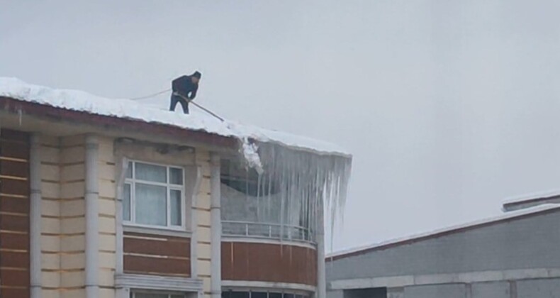 Bitlis’te beline ip bağlayan vatandaş, çatıda kar temizliği yaptı